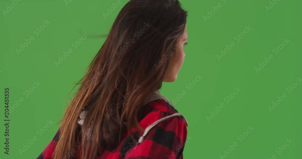 Rear view of woman standing and looking at greenscreen with hair blowing in wind