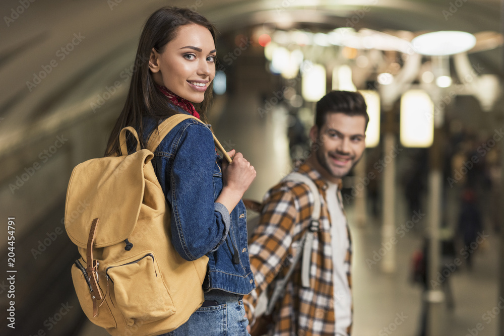  smiling female traveler with backpack and boyfriend at subway station