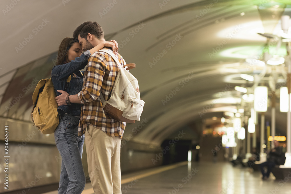 two stylish tourists embracing each other at subway station