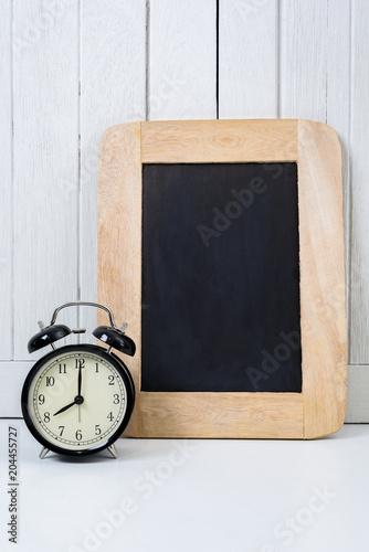 Chalkboard and Alarm clock on Office desk white wooden vintage background