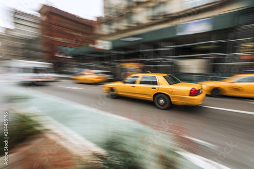 A traditional NYC taxicab drives down a Manhattan street with motion blur captured with slow shutter speed directly in image
