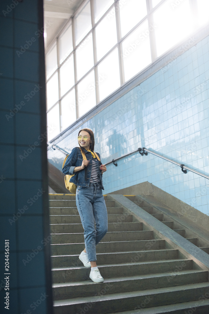 young stylish female tourist in sunglasses with backpack going downstairs at subway young stylish female tourist in sunglasses with backpack going downstairs at subway