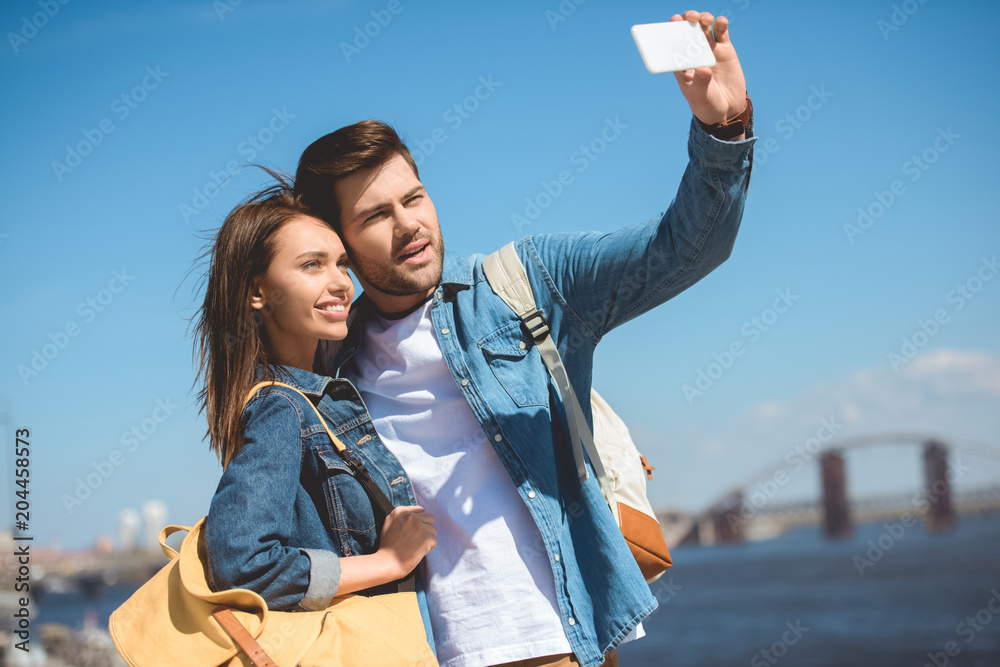 young stylish tourists taking selfie on smartphone young stylish tourists taking selfie on smartphone