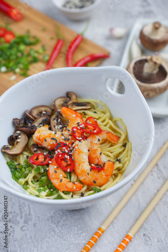 Hot asian wok noodles with shrimps and mushrooms, Preparation ramen, Gray background, Closeup