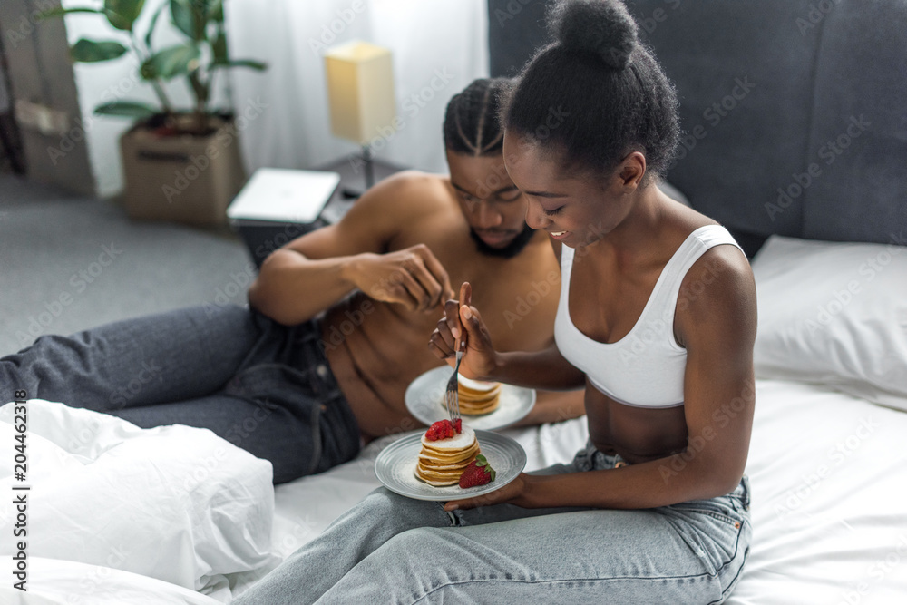 african american couple eating delicious pancakes on breakfast in bedroom african american couple eating delicious pancakes on breakfast in bedroom