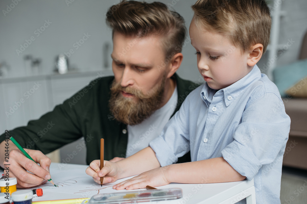father and cute little son with colorful pencils drawing pictures together at home father and cute little son with colorful pencils drawing pictures together at home
