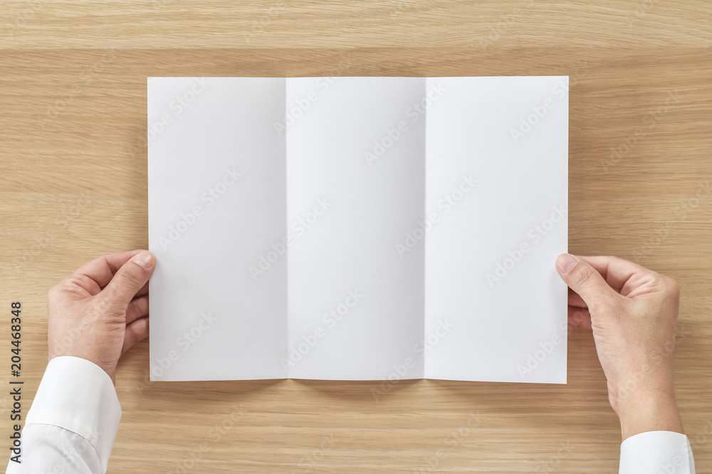 Trifold pamphelt mock up flyer brochure design A4 size paper in business man's hand for template illustration mockup, flatlay on wood table from top view Trifold pamphelt mock up flyer brochure design A4 size paper in business man's hand for template illustration mockup, flatlay on wood table from top view