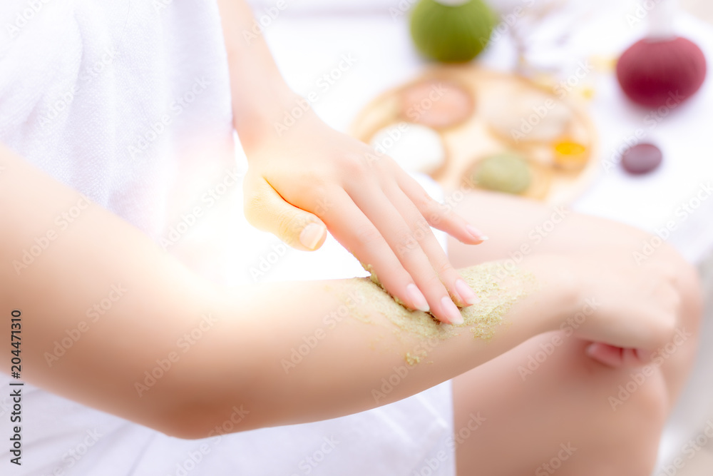 Fototapeta premium Charming beautiful woman use herbal scrubs for scrubbing the old skin cells at her beautiful arm that makes better nice skin and skin rejuvenation. Gorgeous girl scrub skin by herself at luxury hotel