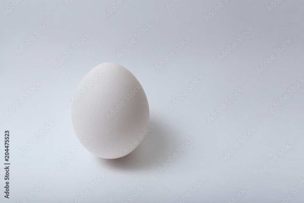 One white egg on white background. Minimalism. One white egg on white background. Minimalism.