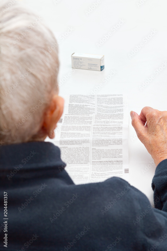 Naklejka premium old woman unable to read drug package leaflet