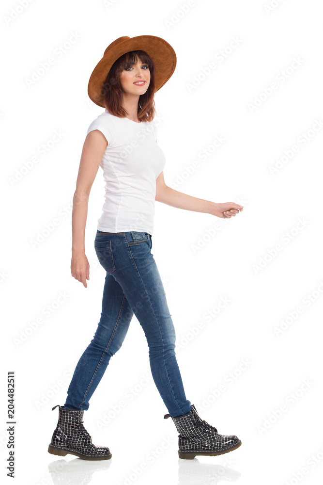 Young Woman In White T-Shirt And Hat Is Walking And Looking At Camera