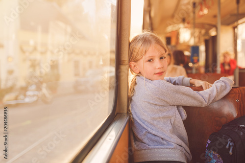 Young girl taking tram on a sunny summer afternoon