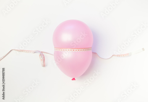 Balloon tied measuring tape on white background. Weight loss, slim body, healthy lifestyle concept. The waist measurement.