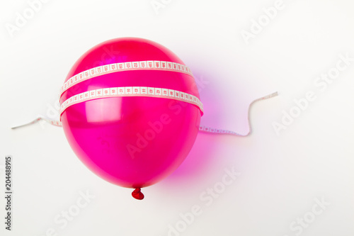 Balloon tied measuring tape on white background. Weight loss, slim body, healthy lifestyle concept. The waist measurement.