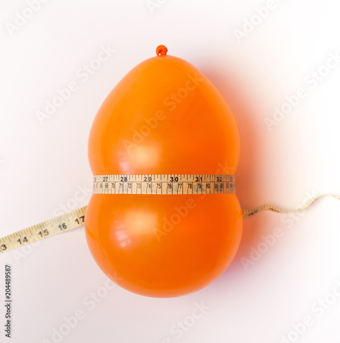 Balloon tied measuring tape on white background. Weight loss, slim body, healthy lifestyle concept. The waist measurement.