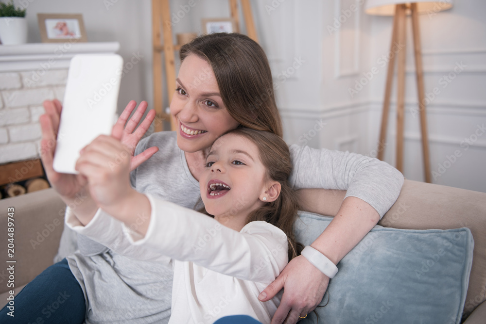 Having fun. Pretty delighted mummy and daughter smiling and taking selfies Having fun. Pretty delighted mummy and daughter smiling and taking selfies