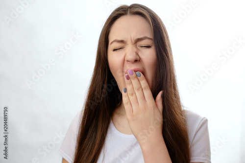 young woman yawns on white background
