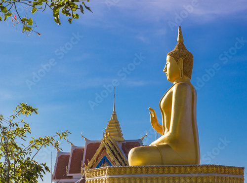 Golden budha statue by morning sunlight with blue sky background.