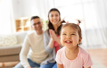 family and people concept - happy little daughter with mother and father at home
