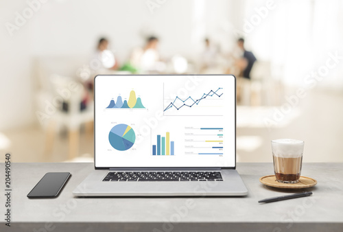 Laptop on wooden table showing charts and graph photo