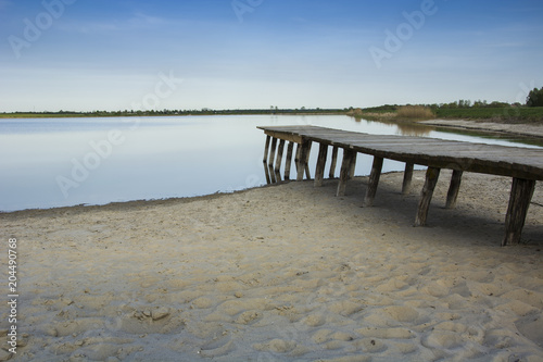 Wooden plank deck, lake and sandy shore