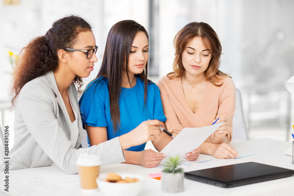business, teamwork and people concept - female team or businesswomen discussing papers at office business, teamwork and people concept - female team or businesswomen discussing papers at office