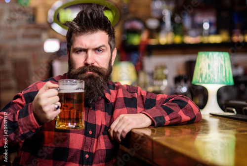 Fotografie Hipster with beard holds glass with beer, raising up, cheers