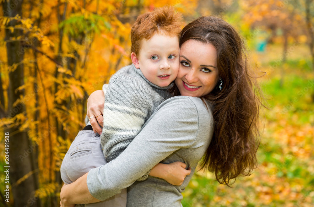 Happy family: mother and child sonr have fun in autumn on autumn park. Young Mother and kid girl hugging in leaves at fall. Happy family: mother and child sonr have fun in autumn on autumn park. Young Mother and kid girl hugging in leaves at fall.