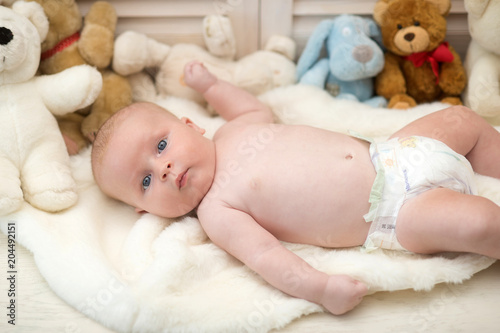 Infant with blue eyes and curious face on light blanket © be free