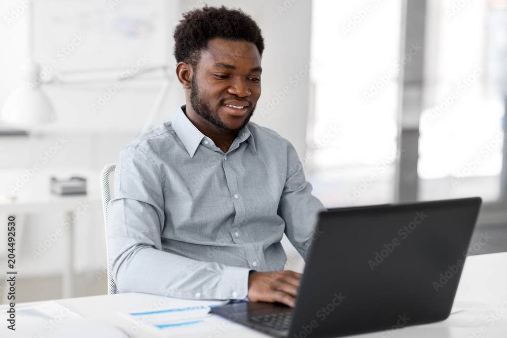 business, people and technology concept - african american businessman with laptop computer working at office business, people and technology concept - african american businessman with laptop computer working at office
