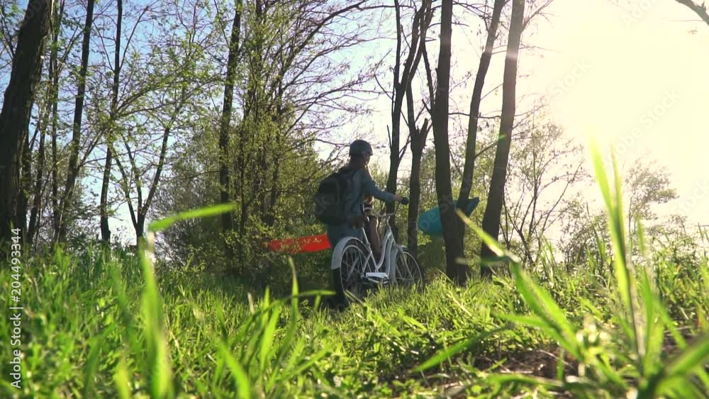 Bottom view as a pair of cyclists walking through the forest and rolling bicycles Bottom view as a pair of cyclists walking through the forest and rolling bicycles