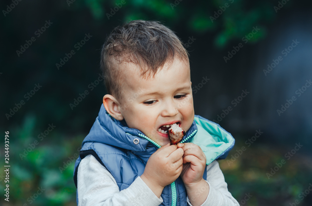 baby, little boy eating a piece of shish kebab meat, outdoors baby, little boy eating a piece of shish kebab meat, outdoors