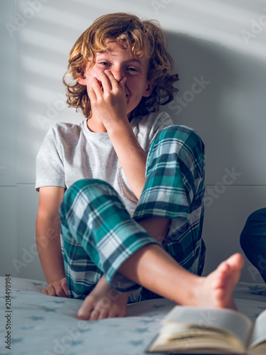 Boy smelling foot on bed