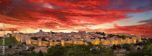 Walls of Medieval city of Avila at sunset with lights on, Spain photo