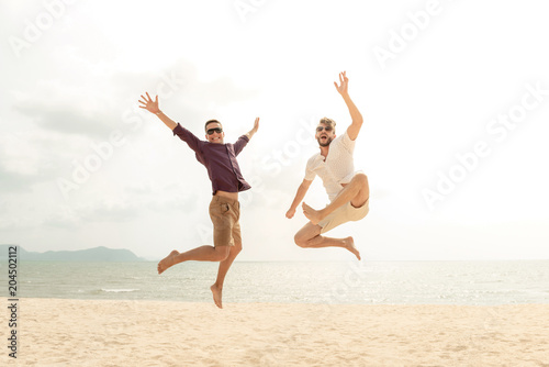 Young energetic happy tourist men jumping at the beach