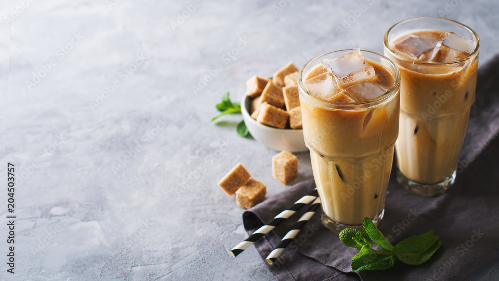 Iced coffee in tall glasses with cream and pieces of sugar, mint and straw - obrazy, fototapety, plakaty 
