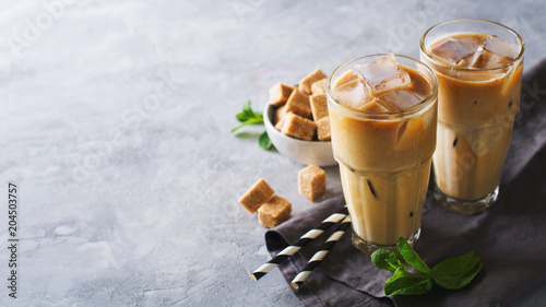 Leinwand Poster Iced coffee in tall glasses with cream and pieces of sugar, mint and straw