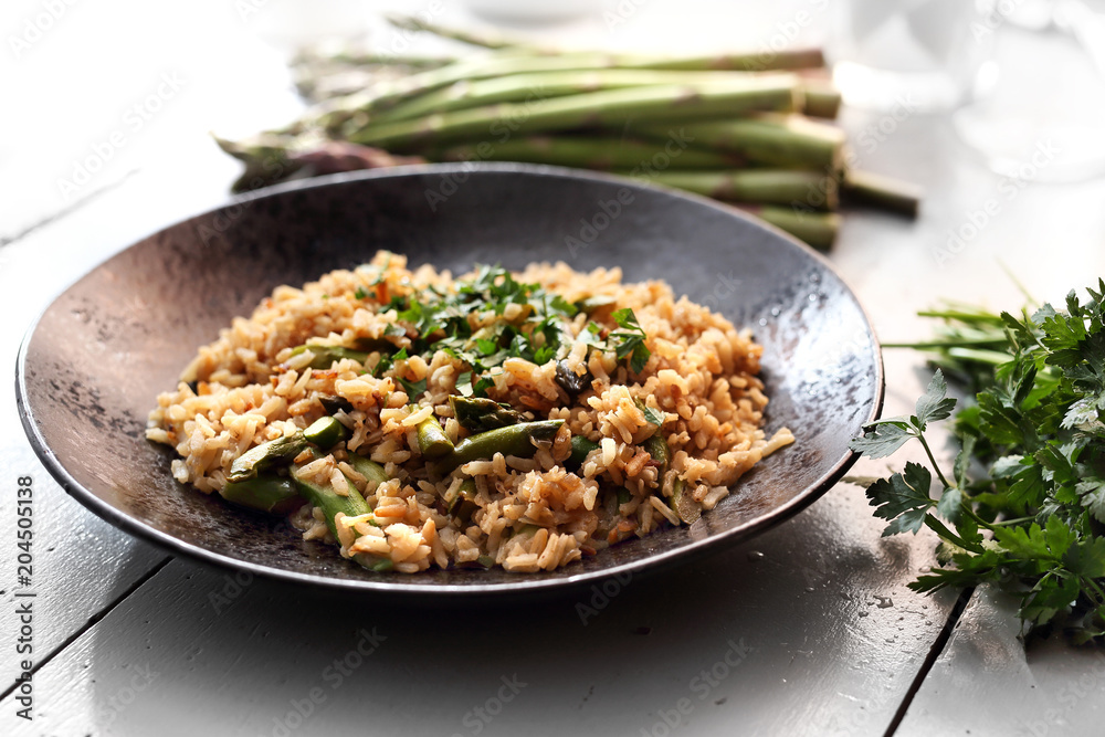 Szparagi. Potrawa z brązowego ryżu i szparagów podana na talerzu.