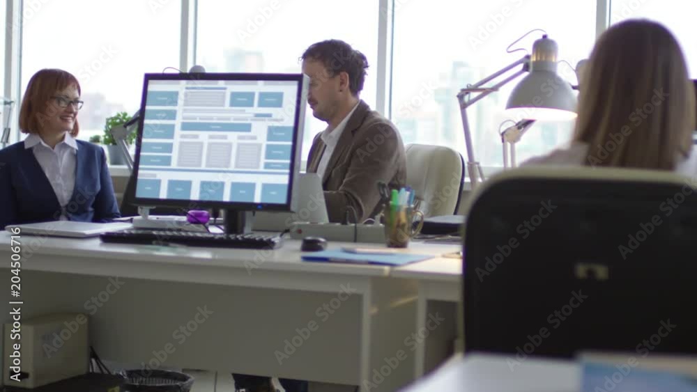 Tracking shot of young paraplegic businesswoman talking with male colleague, taking documents and riding wheelchair to office desk Tracking shot of young paraplegic businesswoman talking with male colleague, taking documents and riding wheelchair to office desk