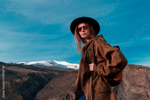 Beautiful young woman with retro backpack on the top of cliff amazing mountain range landscape. Sunset. Hipster. Adventure. Travel lifestyle. Copy space.