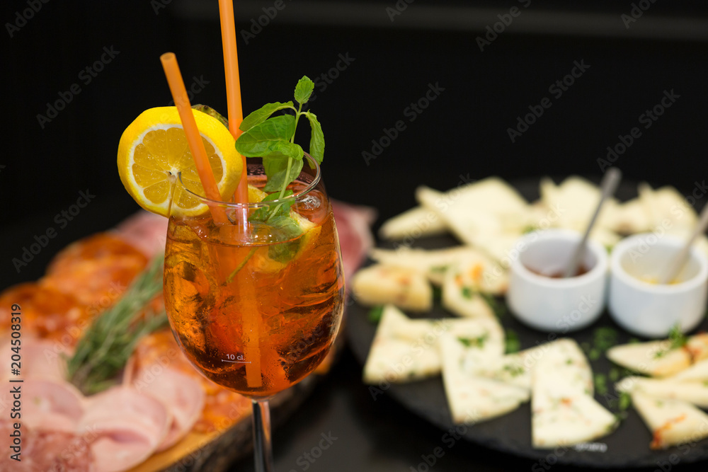 Traditional italian aperitif with proscioutto, mortadella sausage, cheese and aperol spritz drink
