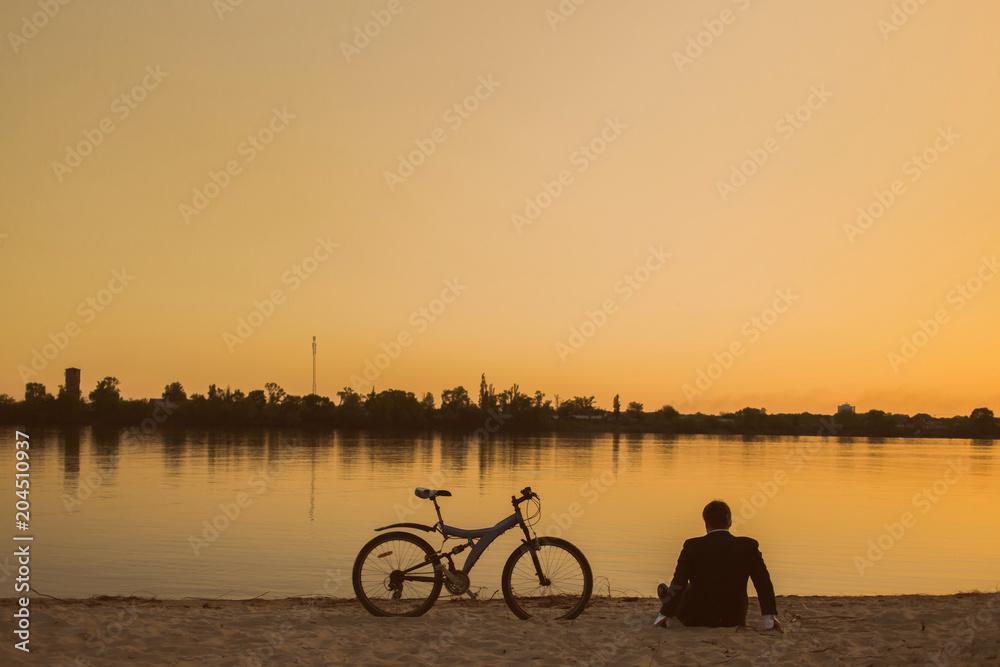 Businessman with a bicycle on the beach. Back view Businessman with a bicycle on the beach. Back view