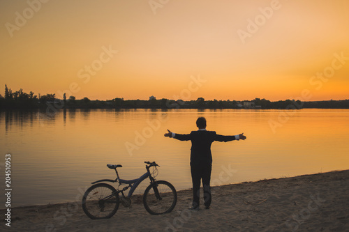 Businessman with a bicycle on the beach. Back view