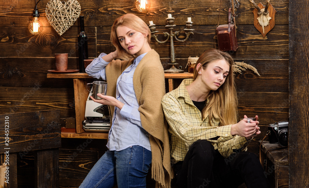 Mom and daughter spend soulful evening, interior background. Girls have soulful conversation with drinks. Support and sympathy concept. Girls on relaxed faces hold metallic mugs, enjoy coziness Mom and daughter spend soulful evening, interior background. Girls have soulful conversation with drinks. Support and sympathy concept. Girls on relaxed faces hold metallic mugs, enjoy coziness
