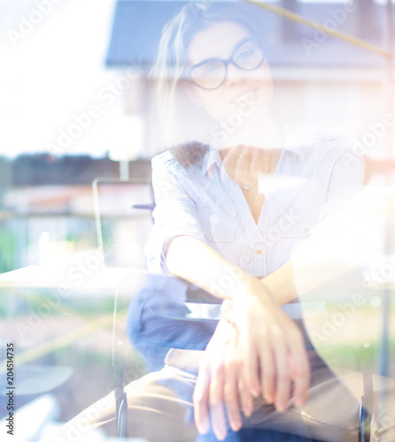 Young woman sitting at office table with laptop,view through window. Young woman
