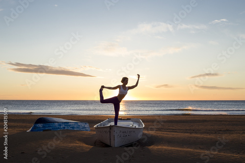 chica al amanecer practicando yoga sobre barca