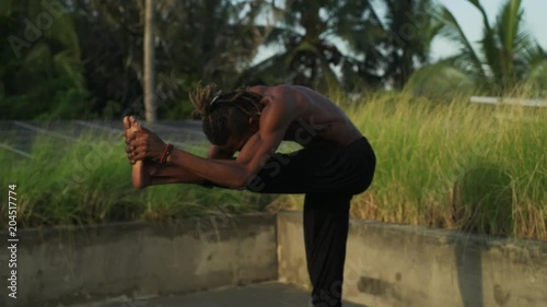 Man do standing head to knee yoga pose roof top solar battery rapid slow motion photo