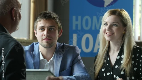 A young couple shaking hands with their banker after receiving a home loan