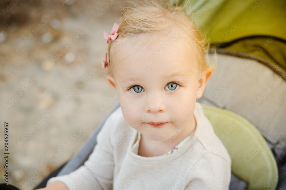 Close up portrait of a cute little girl in a stroller.