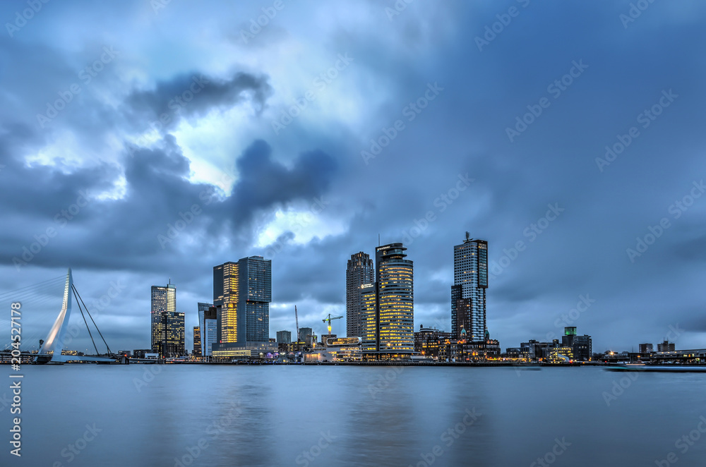 A dramatic sky at dwan over the Erasmus bridge and the Kop van Zuid modern highrise in Rotterdam, The Netherlands A dramatic sky at dwan over the Erasmus bridge and the Kop van Zuid modern highrise in Rotterdam, The Netherlands